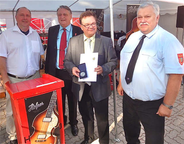 Klaus Schöller (2.v.r.) hat gleich zwei Gründe zur Freude: Der Inhaber der Musikinstrumentenfirma Höfner feiert dieses Jahr zum einen 125-jähriges Firmenjubiläum und wurde zum anderen auf dem Gelände der Feuerwehr Hagenau für sein Engagement für Brandschutz von Landrat Eberhard Irlinger (2.v.l.) und Kreisbrandrat Harald Schattan (r.) mit der ersten Ehrenmedaille des Kreisfeuerwehrverbandes Erlangen-Höchstadt ausgezeichnet. Schon seit 2005 existiert eine eigene Löschgruppe Höfner. Diese besteht aus zahlrei