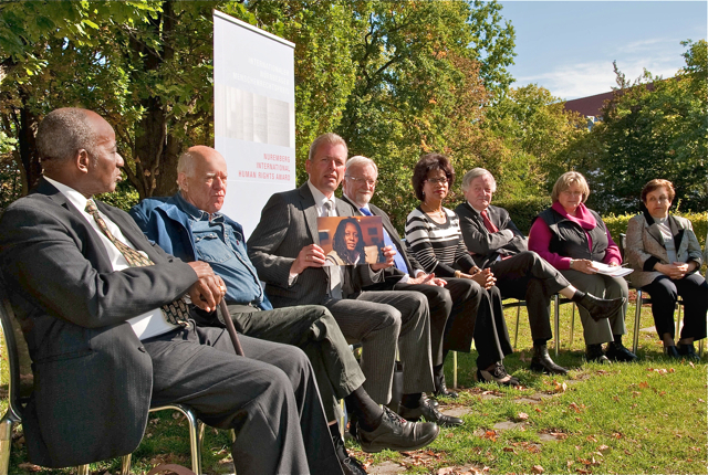 Bekanntgabe der Trägerin des Internationalen Nürnberger Menschenrechtspreises 2013 im Garten des Museums Tucherschloss: Oberbürgermeister Dr. Ulrich Maly präsentiert ein Foto der Preisträgerin Kasha Jacqueline Nabagesera gemeinsam mit den Jury-Mitgliedern (v.l.n.r.) Prof. Dr. Maurice Glèlè-Ahanhanzo, Dani Karavan, Prof. Dr. h.c. Gareth Evans, Angela Melo, Prof. Dr. Theo van Boven, Dolmetscherin Ulrike Seeberger und Shirin Ebadi. Foto: Christine Dierenbach / Stadt Nürnberg