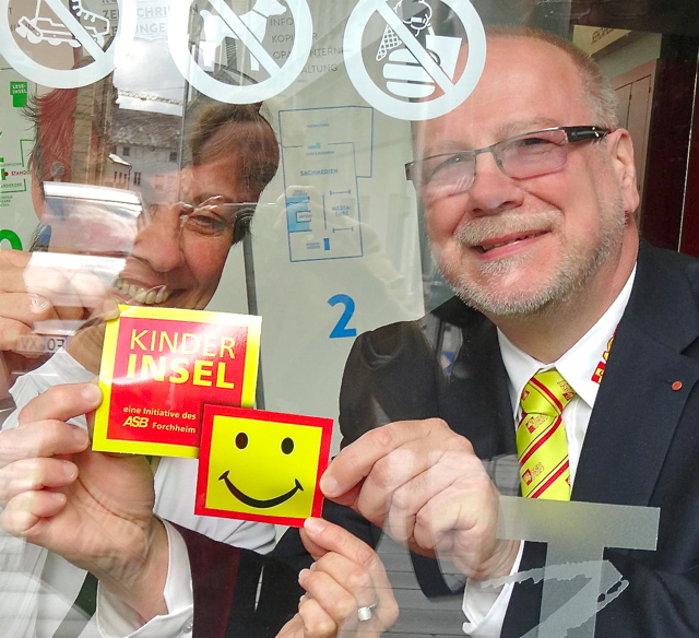Doris Koschyk, Leiterin der Stadtbücherei, und ASB- Geschäftsführer Wolfgang Caps bringen den Kinderinsel-Aufkleber an. Foto: Stadt Forchheim