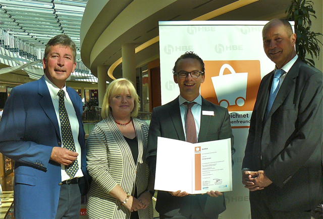 Als erstes Einkaufszentrum der mfi AG haben die Erlangen Arcaden aus den Händen des Geschäftsführers des Handelsverbandes Bayern HBE Uwe H. Werner (l.) und dem Bezirksgeschäftsführer HBE Jan-Jörg Brunner (r.) das Zertifikat für generationenfreundliches Einkaufen, einem bundesweiten Qualitätszeichen, überreicht bekommen. Um das Einkaufslabel zu erhalten, werden Zugangsmöglichkeiten, Ausstattung der Geschäftsräume sowie das Serviceverhalten von den Testerinnen und Testern des HBE überprüft. Die Erlanger Bürge