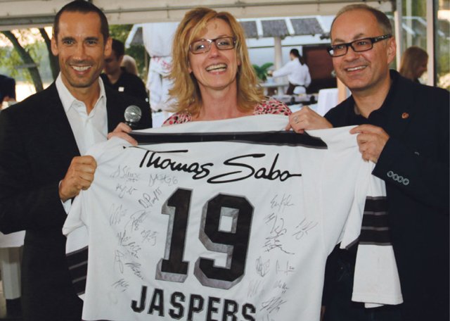 Ice Tigers Geschäftsführer Christoph Sandner (l.) und Tucher Marketing-Direktor Kai Eschenbacher überraschen Strandhaus-Chefin Brigitte Celikaya mit einem Originaltrikot. Foto: John R. Braun