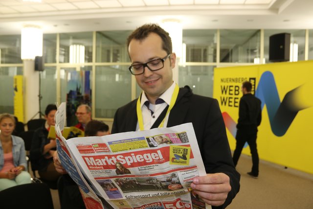 Organisator Ingo di Bella liest im MarktSpiegel einen Artikel zur Nürnberg WebWeek.