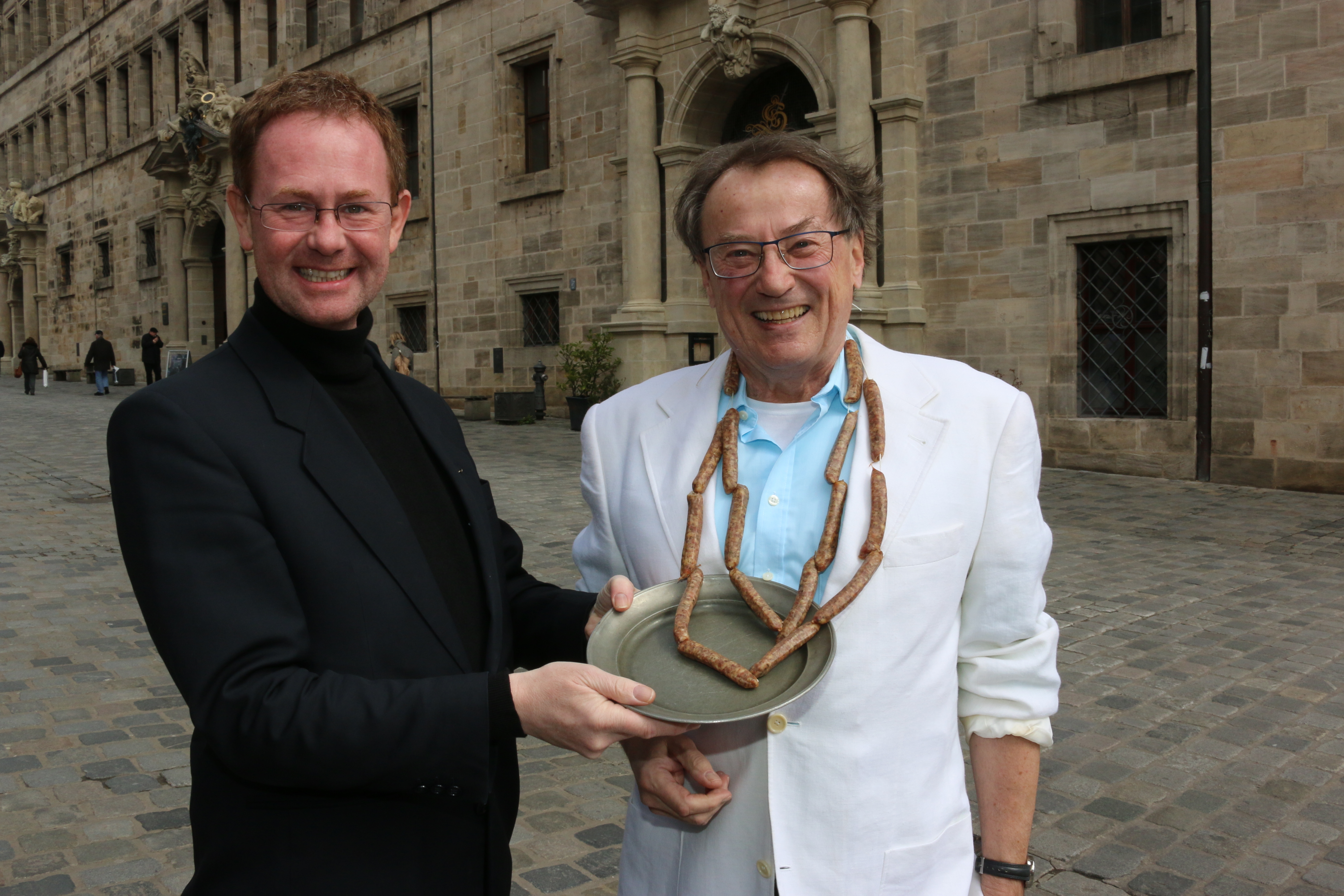 Günter Morsbach (r.) und Kai Behringer stellen den neuen ,,Bratwurstkranz“ vor dem Rathaus vor.