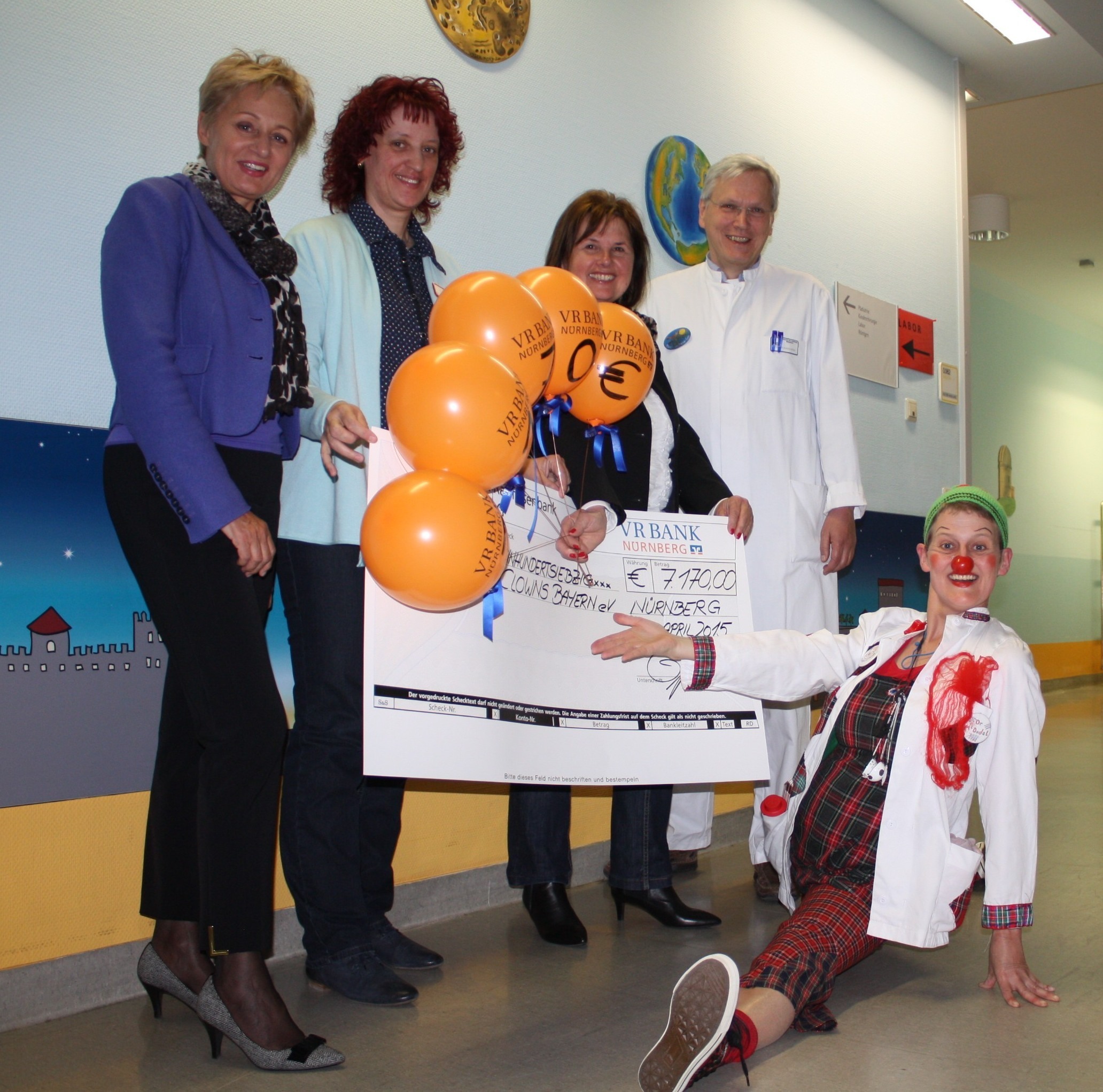 Bei der Spendenübergabe: Zusammen mit KlinikClown „Frau Dr. MC Dudel“ (vorne) freuen sich (v.l.) Brigitte Baur (stellvertretende Vorstandsvorsitzende VR Bank Nürnberg, Petra Meidlinger (Pflegedienstleitung), Edeltraud Mayer (Vorsitzende der Elterninitiative Krebskranker Kinder e.V. Nürnberg) sowie Klinikleiter Prof. Dr. Wolfram Scheurlen. Foto: Victor Schlampp