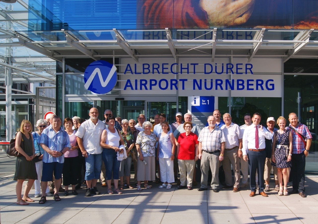 Die Teilnehmer der VNN-Besuchstour am Flughafen vor dem neuen Logo ,,Albrecht Dürer" mit Flughafen-Pressesprecherin Stefanie Schmidts und VNN-Chef Tobias Schmidt (2. und 4. v. r.)