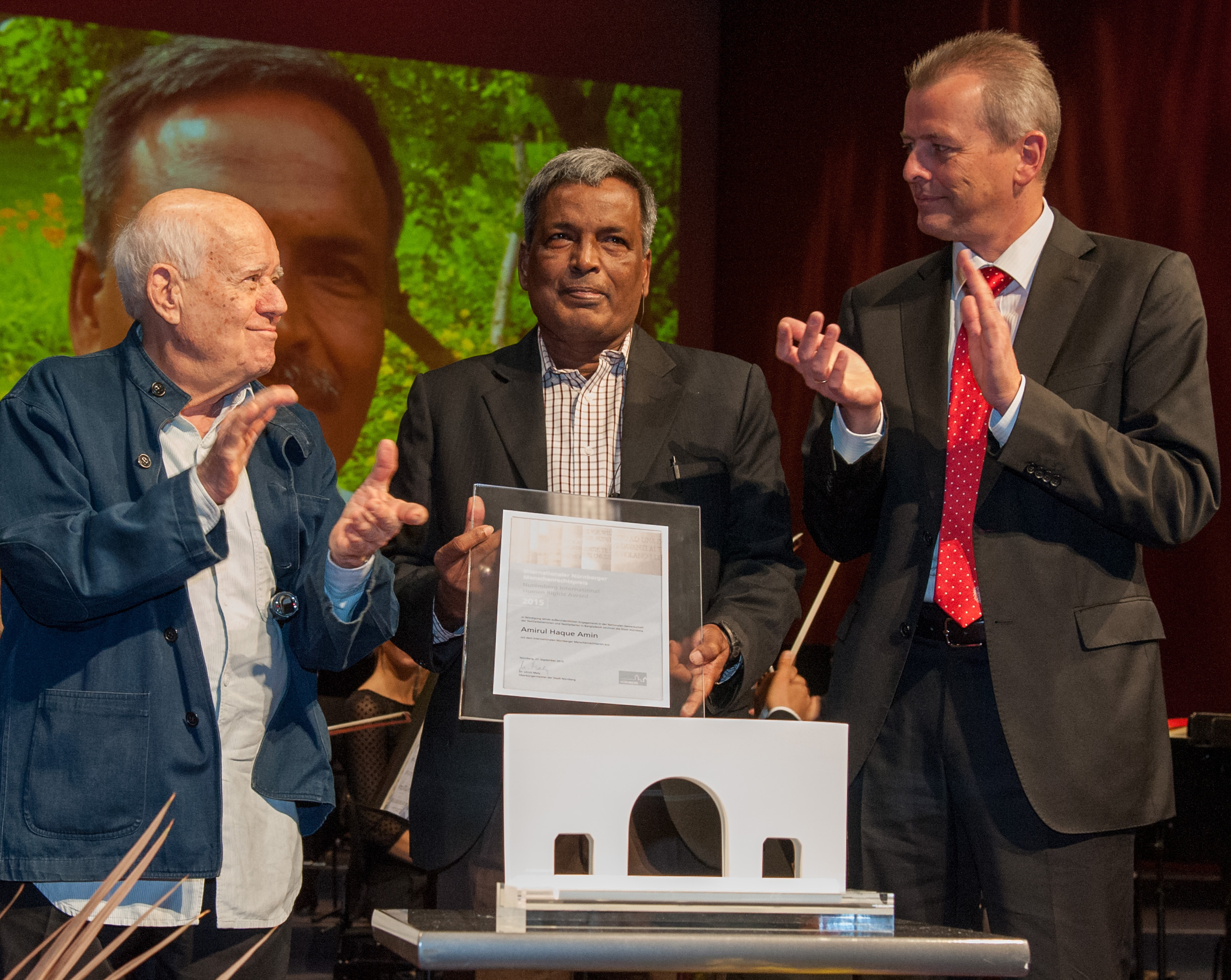 Applaus für Amirul Haque Amin (Mitte): Oberbürgermeister Dr. Ulrich Maly (r.) und der Künstler Dani Karavan, Schöpfer der Straße der Menschenrechte in Nürnberg, bei der Vergabe des Internationalen Nürnberger Menschenrechtspreises im Opernhaus des Staatstheaters Nürnberg.