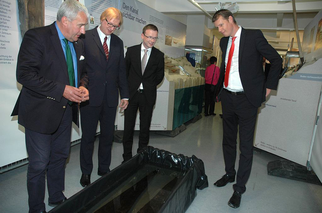 Staatsminister Dr. Ludwig Spaenle, Museumsleiter Jürgen Söllner, Peter Daniel Forster (Bezirksrat) und Oberbürgermeister Matthias Thürauf (v.l.) bewundern bei der Ausstellungseröffnung original Eichenholzbohlen aus dem Jahr 793.