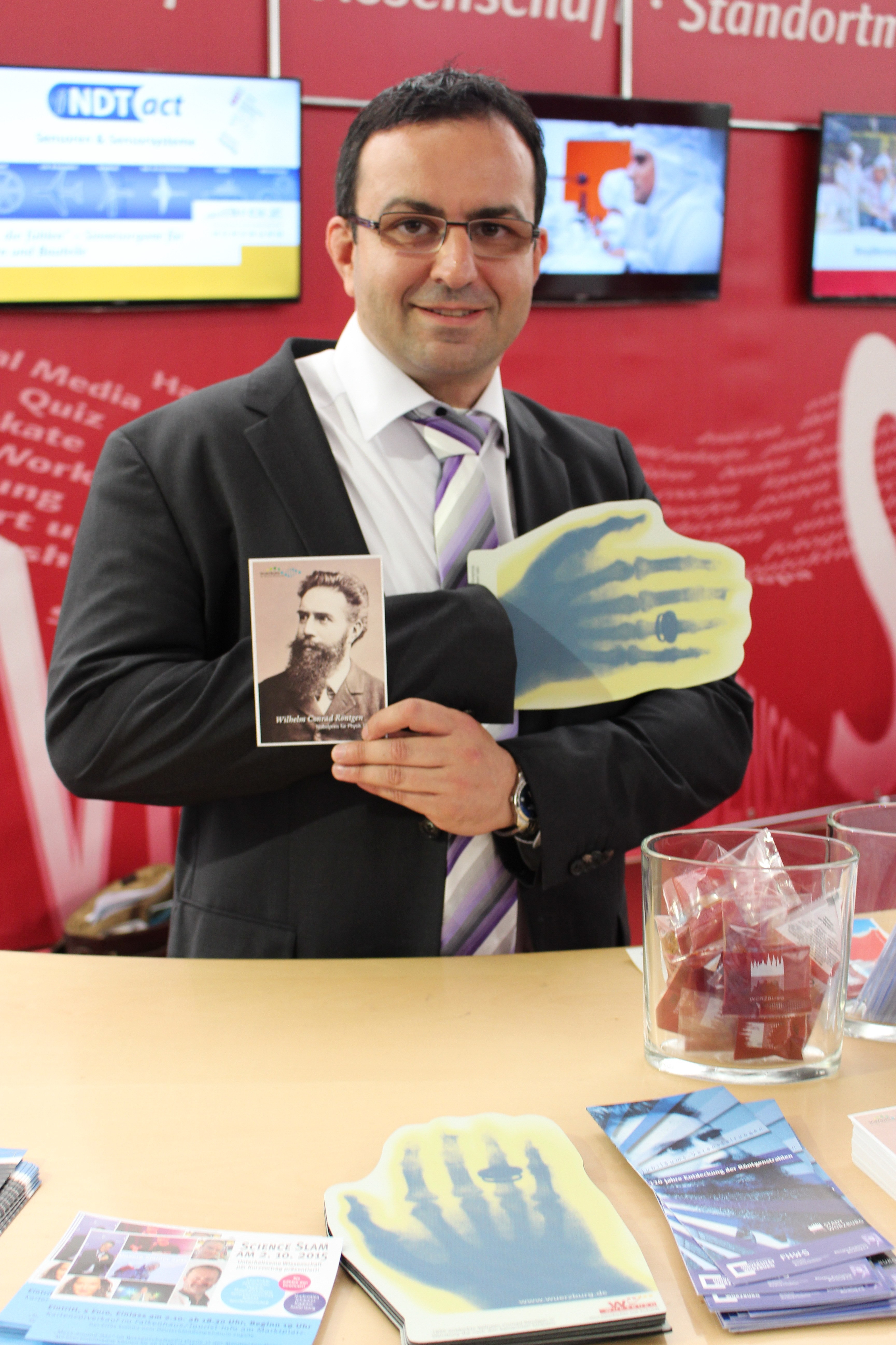 Durchblick: Der Stadtbeauftragte André Hahn mit einer der Nobelpreisträger-Karten und einem Mousepad, das mit der berühmten historischen Röntgenaufnahme spielt.