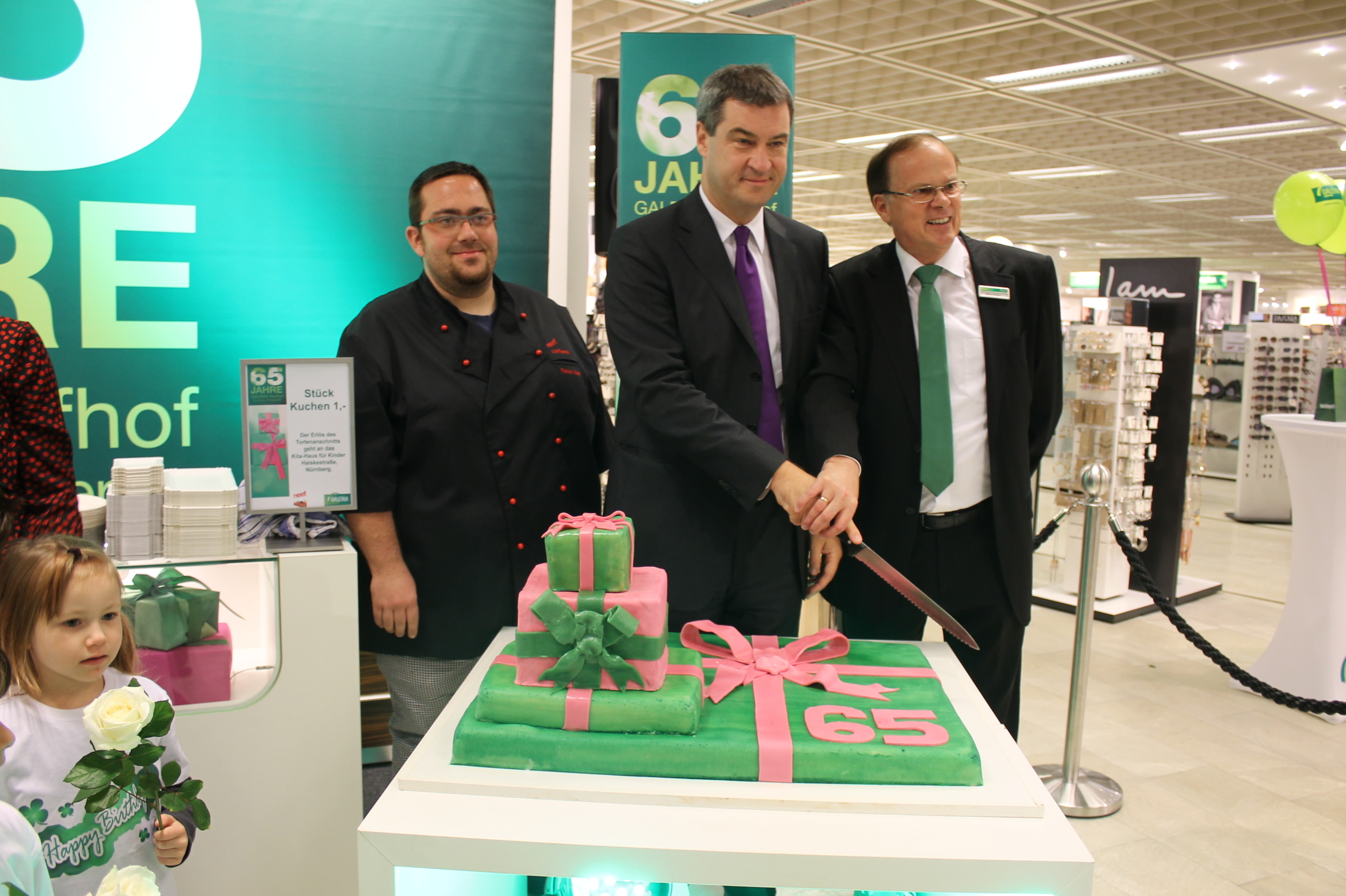 Der Bayerische Finanz- und Heimatminister Dr. Markus (Mitte) Söder mit Galeria Kaufhof Geschäftsführer Walter Enders (r.) beim Anscheiden der Torte.