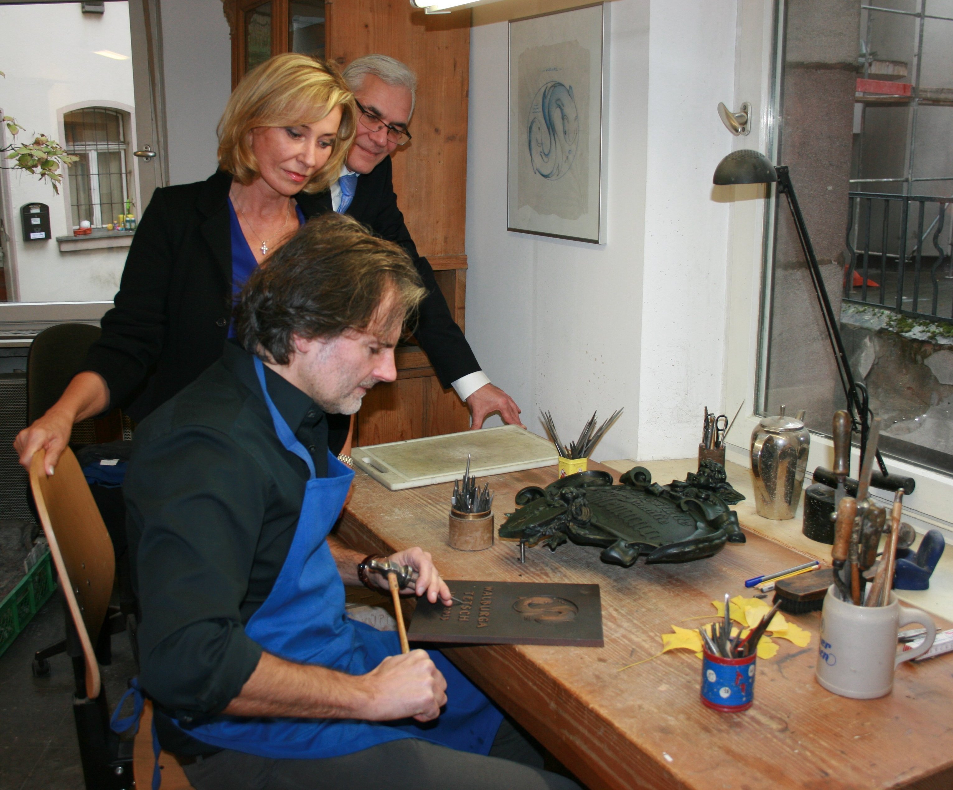 MdB Dagmar Wöhrl und Thomas Weitzenfelder schauen dem Künstler Thomas Haydn über die Schulter.