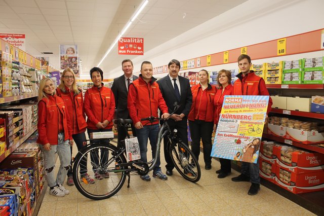 NORMA-Verkaufsleiter Jörg Schuchardt (4.v.l.), NORMA-Bereichsleiter Wilfried Berg (4.v.r.), Filialleiter Dominic Kaiser (r.) und das freundliche NORMA-Team präsentieren den Hauptpreis, der anlässlich des Neueröffnungs-Gewinnspiels, verlost wird.