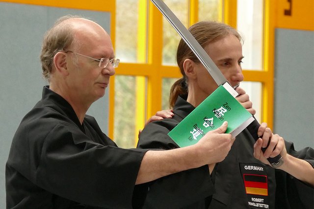 Lehrgangsleiter Rudi Müller (links), Präsident des Bayerischen Iaido Bundes, erklärt hier detailliert anhand der Vorgaben im Iaido-Kommentar wie die Hasso-Haltung ausgeführt werden soll.