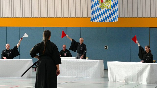 Drei Kampfrichter entscheiden mittels Fahne, wer von den beiden Kontrahenten (Rot und Weiß) den Sieg errungen hat.