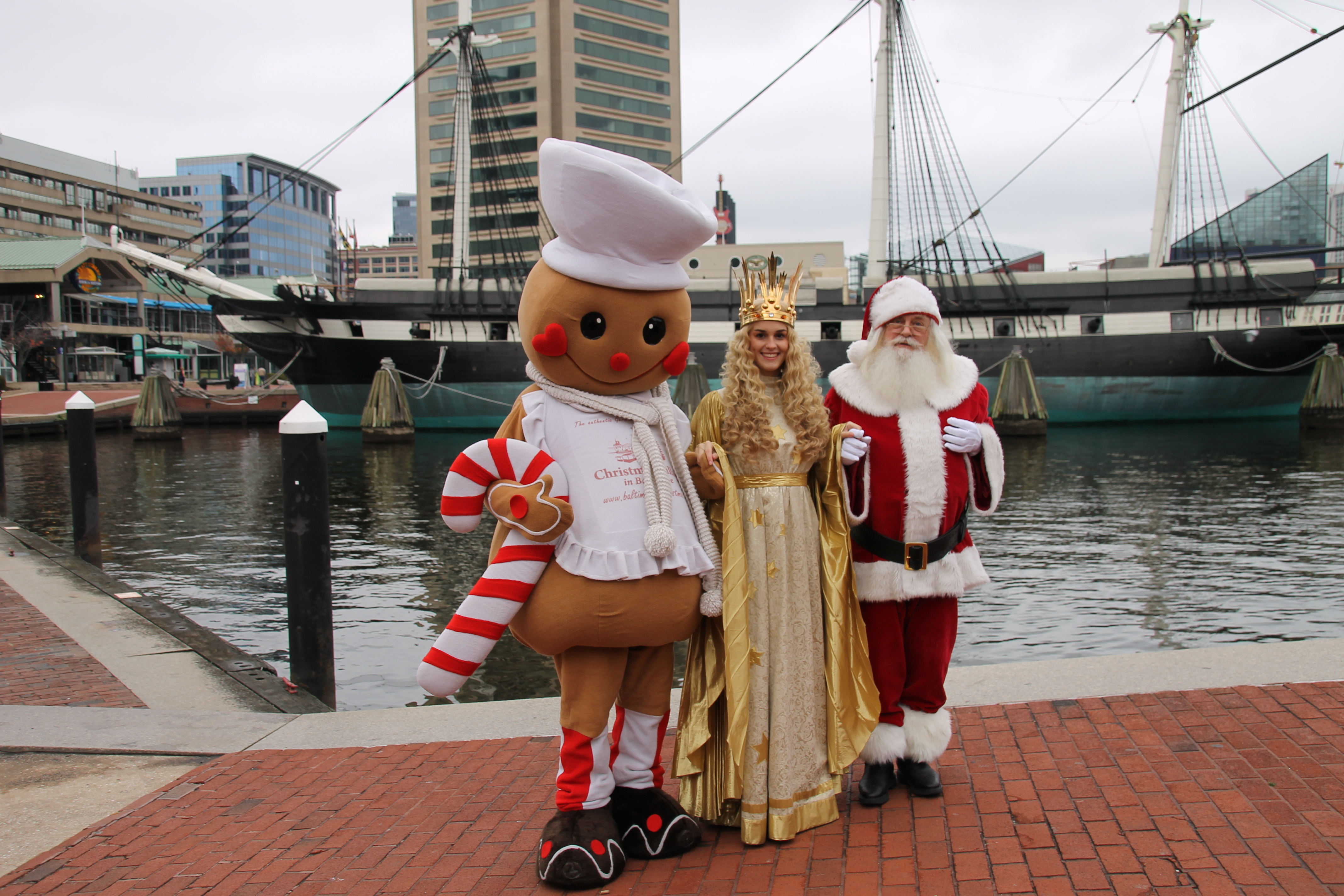 Das Christkind wird im Inner Harbour von Baltimore von Santa Claus und dem Lebkuchemann ,,Gingerman" abgeholt. Gemeinsam spazieren sie zum nahegelegenen Weihnachtsmarkt.
