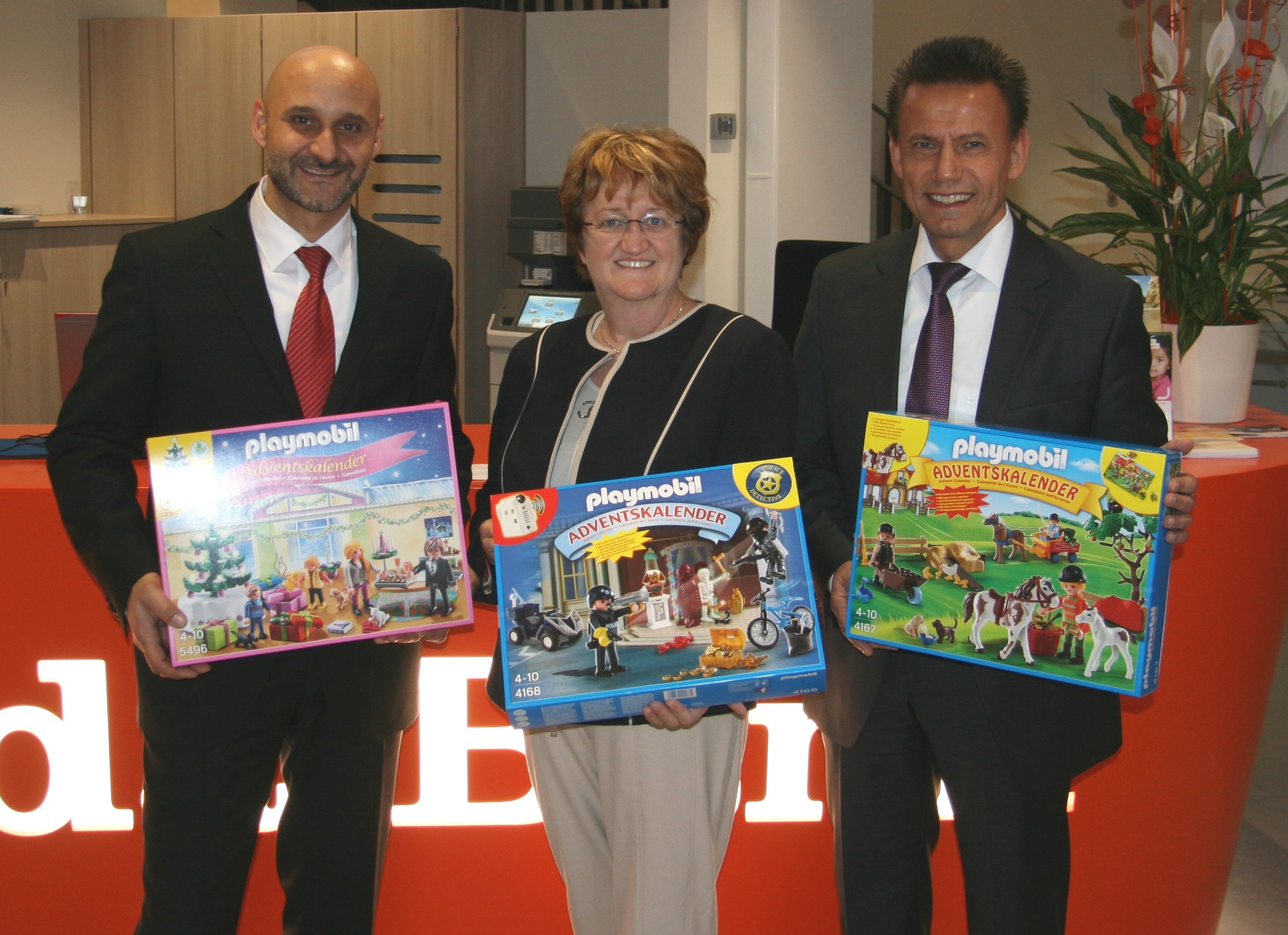Der Fürther Filialleiter Dejan Susak (li.) und Thomas Lang übergeben die Spielzeugkalender an Elisabeth Reichert.