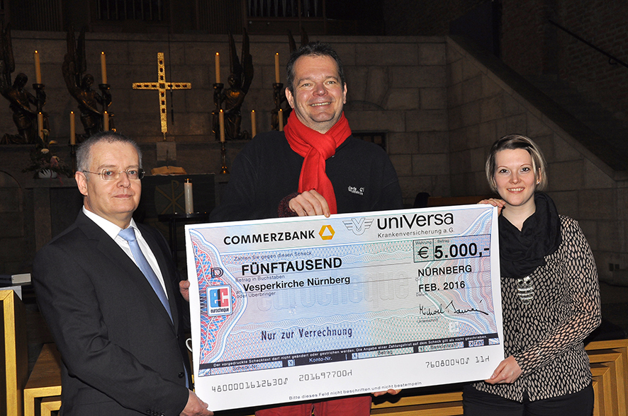 uniVersa-Vorstandsmitglied Michael Baulig (li.) bei der Scheckübergabe an Pfarrer Bernd Reuther; daneben Regina Lösch, Mitarbeiterin der uniVersa, die die Vesperkirche ehrenamtlich unterstützt.