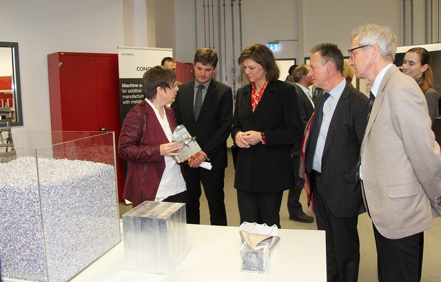 Prof. Dr. Carolin Körner vom Lehrstuhl für Werkstoffwissenschaften (l.) erklärt der Ministerin wie beim selektiven Strahlschmelzen komplexe Bauteile gefertigt werden können. Mit im Bild (v.l.): Prof. Dr. Joachim Hornegger, Präsident der FAU, Fürths Oberbürgermeister Dr. Thomas Jung und Prof. Dr. Robert Singer, Leiter der VerTec.