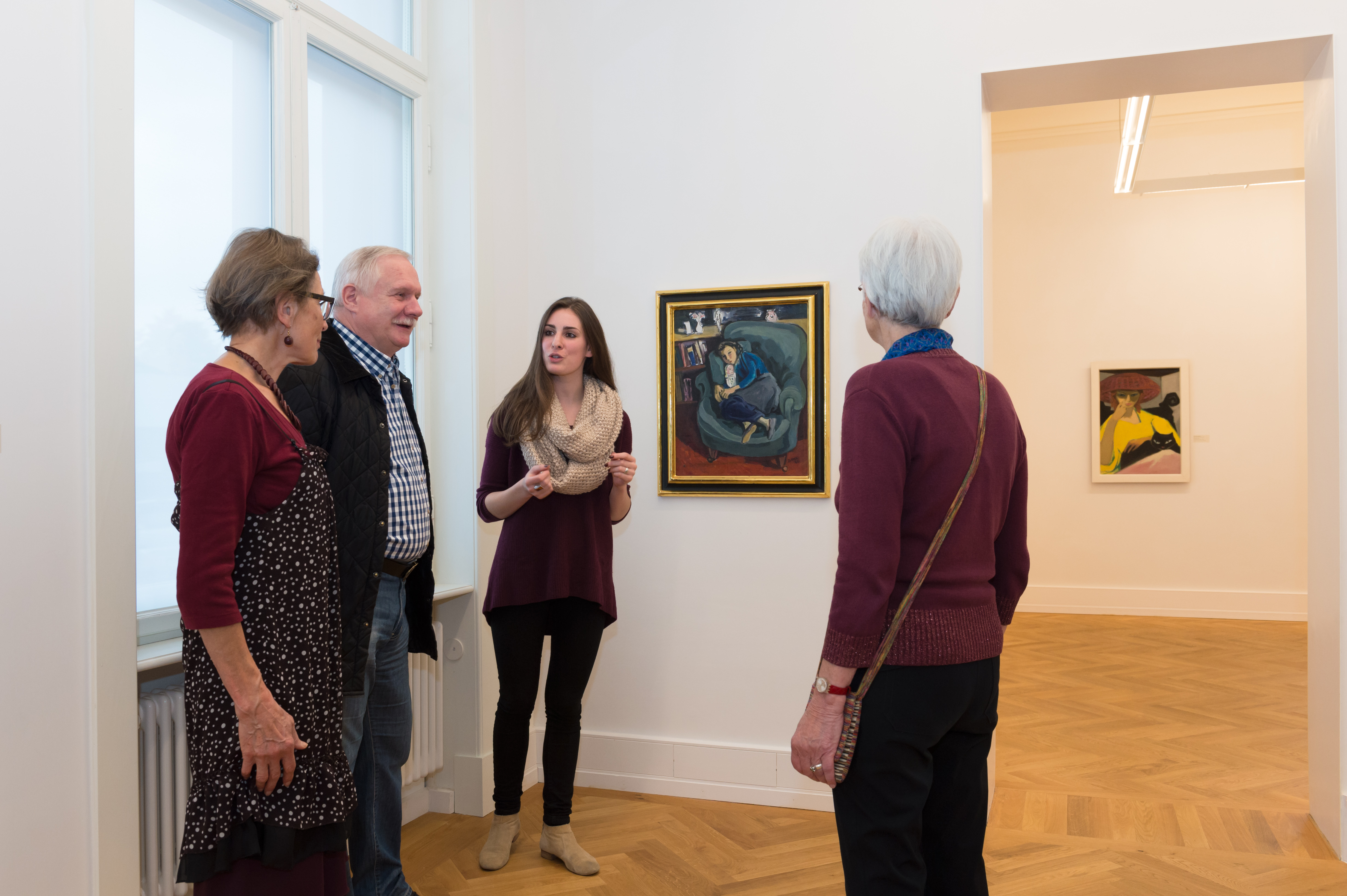 Eine Besuchergruppe in der Kunstvilla im Gespräch vor dem Bild „Mädchen im Sessel“ (1949) von Dore Meyer-Fax.