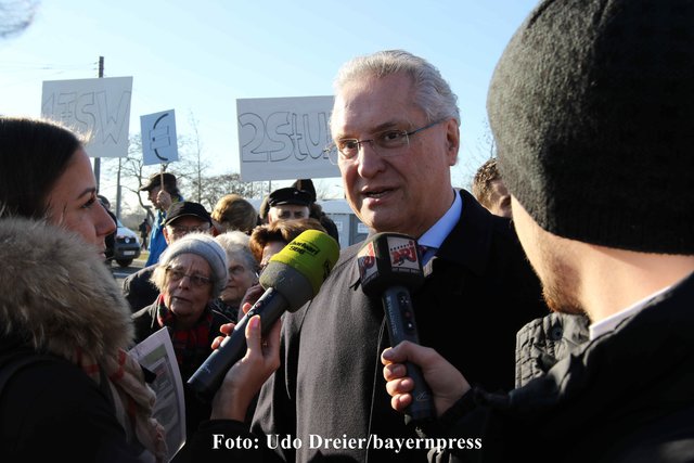 Innenminister Joachim Herrmann umringt von Mikrofonen.