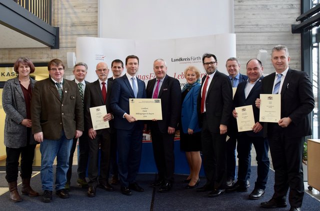 Umrahmt von den Bürgermeistern der Landkreis-Kommunen und Landtagsabgeordneten präsentieren Matthias Dießl und Ludwig Spaenle das Siegel "Bildungsregion in Bayern".