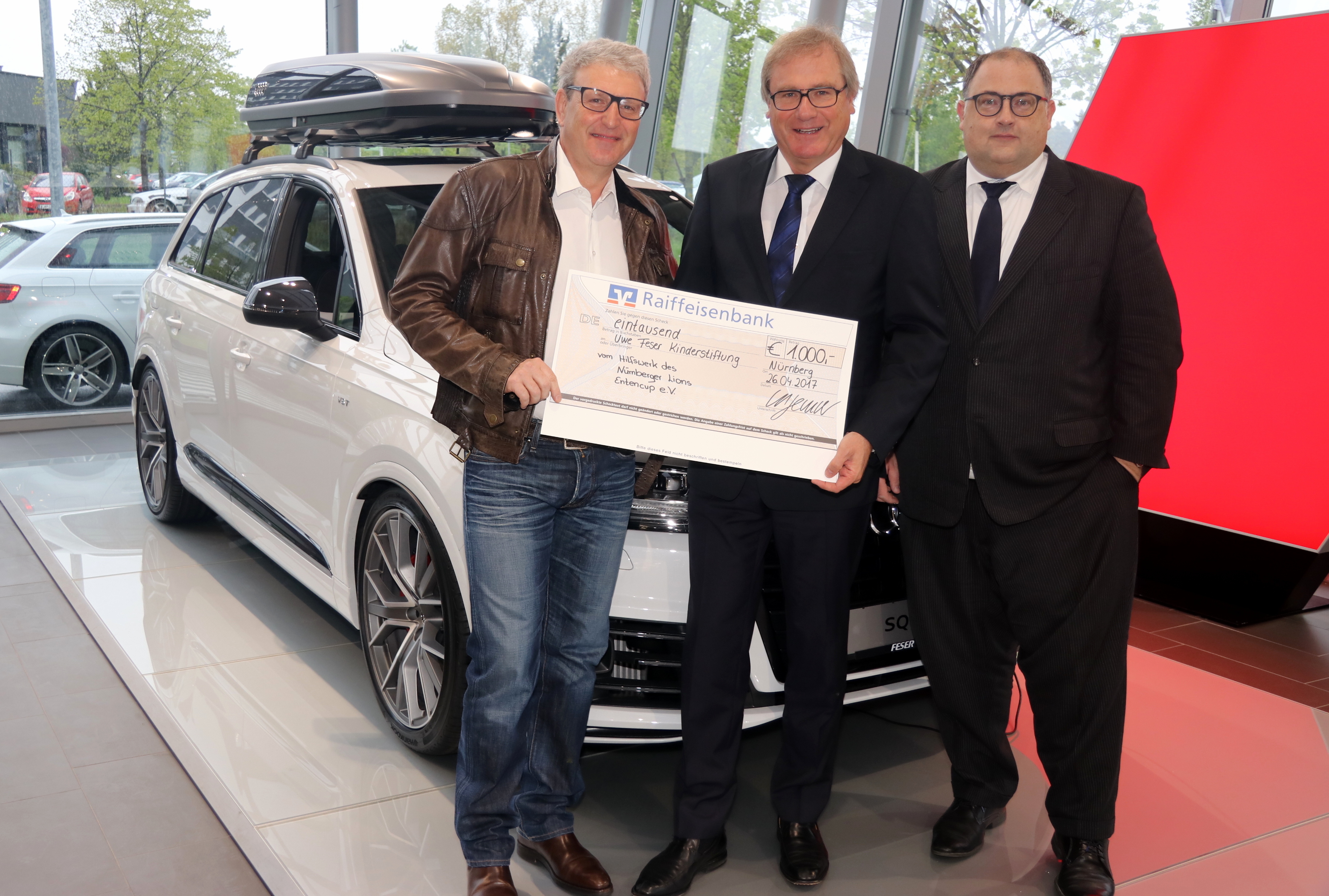 Dr. Michael Sauter (Lions Club) übergab den Scheck an Uwe Feser zugunsten seiner Kinderstiftung. Mit dabei war auch Markus Rehm (Geschäftsführer Audi + VW Nürnberg-Marienberg) (v.l.n.r.)