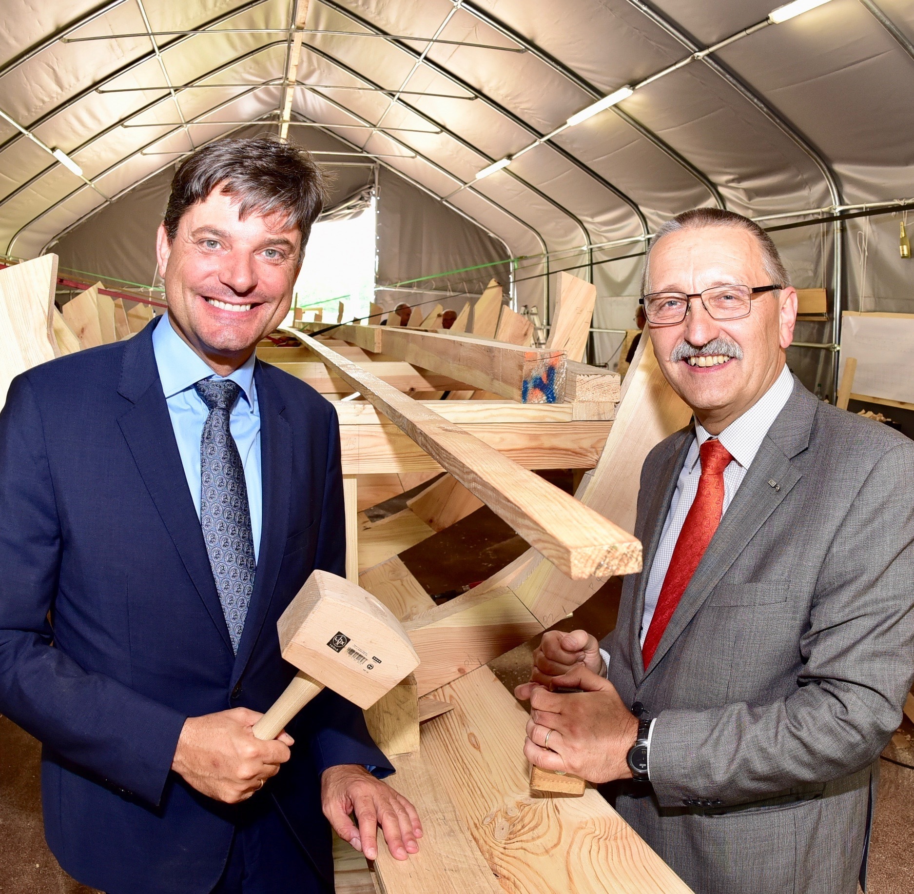 FAU-Präsident Prof. Dr.-Ing. Joachim Hornegger und FAU-Kanzler a.D. (1988-2014) Thomas Schöck mit Holzhammer und Hobel am Rumpf des Römerbootes. Foto: © Peter Maskow
