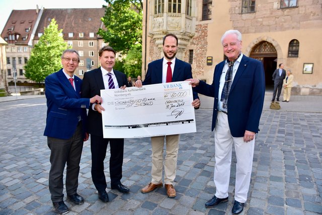 Prof. Dr. Franz Janecek (li.), Dirk Helmbrecht (2.v.li.) und Dr. Joachim Reitenspiess (re., alle Lions Club Nürnberg Noris) überreichen den Scheck für die Sanierungskosten an Pfarrer Jonas Schiller. Foto: © Peter Maskow
