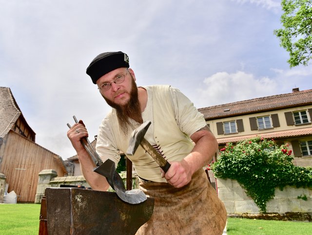 Mit Hammer, Zange und Amboss dengelt der Schmied ein Rüstungsteil zurecht. Foto: © Peter Maskow