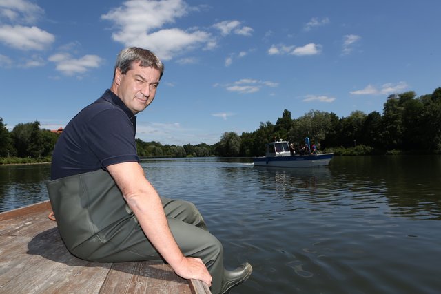 In Fischerhosen sitzt Minister Söder am Bug des kleinen Schiffes, das ihn auf die Insel bringt. Foto: © Sven Grundmann