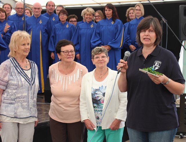 Die Vorsitzende der Frauen Union Schwanstetten, Margit Fischer (l.), hat Doris Hutflesz (r.) einen Scheck in Höhe von 500 Euro für die Jugendarbeit des 1. FC Schwand  übergeben. Der Erlös stammt vom Getränke- und Kuchenverkauf bei verschiedenen Veranstaltungen der Frauen Union. Die Gospel-Gruppe von Jimmy Brooks (im Hintergrund) hatte das Festprogramm mitgestaltet. | Foto: © Renate Brügmann