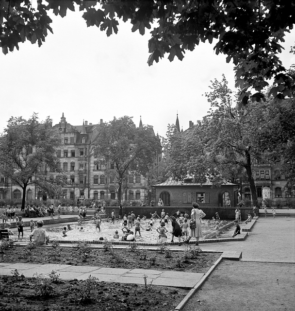 In der Veit-Stoß-Anlage 1950. Sie liegt zwischen Fürther, Müllner- und Glockendonstraße. Der kleine Park mitten in Gostenhof erhielt 1876 seinen Namen nach dem Nürnberger Bildhauer und Bildschnitzer Veit Stoß (um 1447–1533). In den 1950er Jahren war die Anlage ein beliebter Treffpunkt im Stadtteil, der ausreichend Platz zum Spielen und Toben für die Kinder bot. Eine besondere Attraktion in den heißen Sommermonaten war das Wasserbassin, in dem man sich abkühlen konnte. Foto: © Hochbauamt