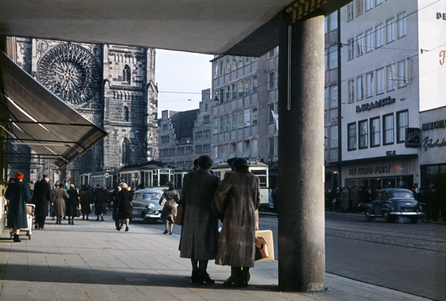 Karolinenstraße um 1954. Bis zur Umwandlung in eine Fußgängerzone floss reger Verkehr durch die Karolinenstraße. Sowohl Autos als auch die Straßenbahn prägten das Straßenbild. Das Gebäude neben der Lorenzkirche mit dem auffallenden Treppengiebel beherbergt die Commerzbank. Das in historisierenden Formen errichtete Bankhaus stammt aus dem Jahr 1926. Foto: © Hochbauamt