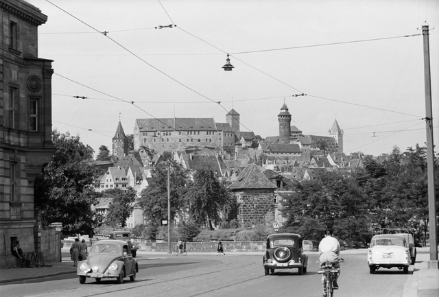 Blick vom Spittlertorgraben zur Burg, Juni 1955. Kriegsspuren wie Zerstörungen und Baulücken lassen sich kaum ausmachen. Die Burg, Wahrzeichen der Stadt, ist wiederhergestellt und erstrahlt in altem Glanz, obwohl der Gesamtwiederaufbau der Anlage erst 1976 beendet war. Typisch für die 1950er Jahre ist der noch recht mäßige Autoverkehr am Spittlertorgraben. Foto: © Hochbauamt