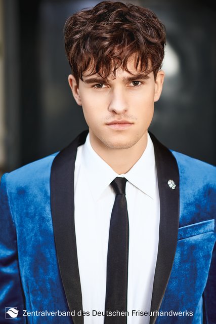 Die wilde Seite des James Dean. Mit diesem locker-gewellten Look trägt Mann den absoluten Trend der Saison. Der strukturiert-gestylte Oberkopf nähert sich dem „Bold Cut“ an. Die obere Partie ist voller gehalten und setzt sich somit deutlich vom Rest ab. Wellen im Stirnbereich sorgen selbst im feinen Zwirn für die nötige Coolness. | Foto: Immo Fuchs, Köln / © Zentralverband Friseurhandwerk, Köln