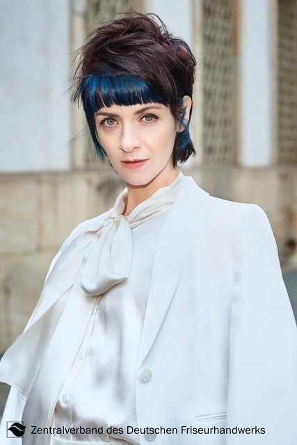 Exzessiv! Kombiniert mit einem eleganten Hosenanzug wird der Mullet in strukturierter, hinten aufgestellter Variante zum echten Statement. Die vordere Partie bleibt dabei glatt und präsentiert sich durch die verschiedenen Blau-Schattierungen auffallend shiny. So entfaltet der Denim-Jeans-Look hier seine ganz besondere Wirkung. | Foto: Immo Fuchs, Köln / © Zentralverband Friseurhandwerk, Köln