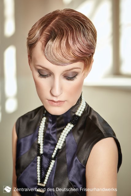 Glamour pur für den großen Auftritt. So wird kurzes Haar zum echten Red-Carpet-Star. Die handgelegte Welle, glanzvoll umhüllt, versprüht Romantik und Eleganz. Ein edles Abendkleid und Perlenaccessoires machen diesen 1920er-Jahre-Look perfekt. | Foto: Immo Fuchs, Köln / © Zentralverband Friseurhandwerk, Köln