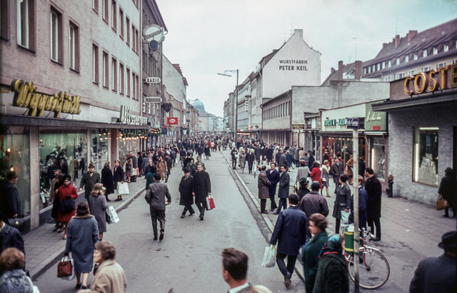 Nach zum Teil heftigen Widerständen wurde 1966 in einer Probe-phase die Breite Gasse zur autofreien Zone umfunktioniert. Da dieser Schritt von der Nürnberger Bevölkerung gut angenommen wurde, konnten in der Folgezeit weitere Fußgängerbereiche in der Altstadt etabliert werden. Nürnberg besitzt somit eine der ältesten Fußgängerzonen in Deutschland. | Foto: Hochbauamt, 1964 und Dezember 1966. (StadtAN A 55 Nr. I-7-1-6 und Nr. I-7-2-10)