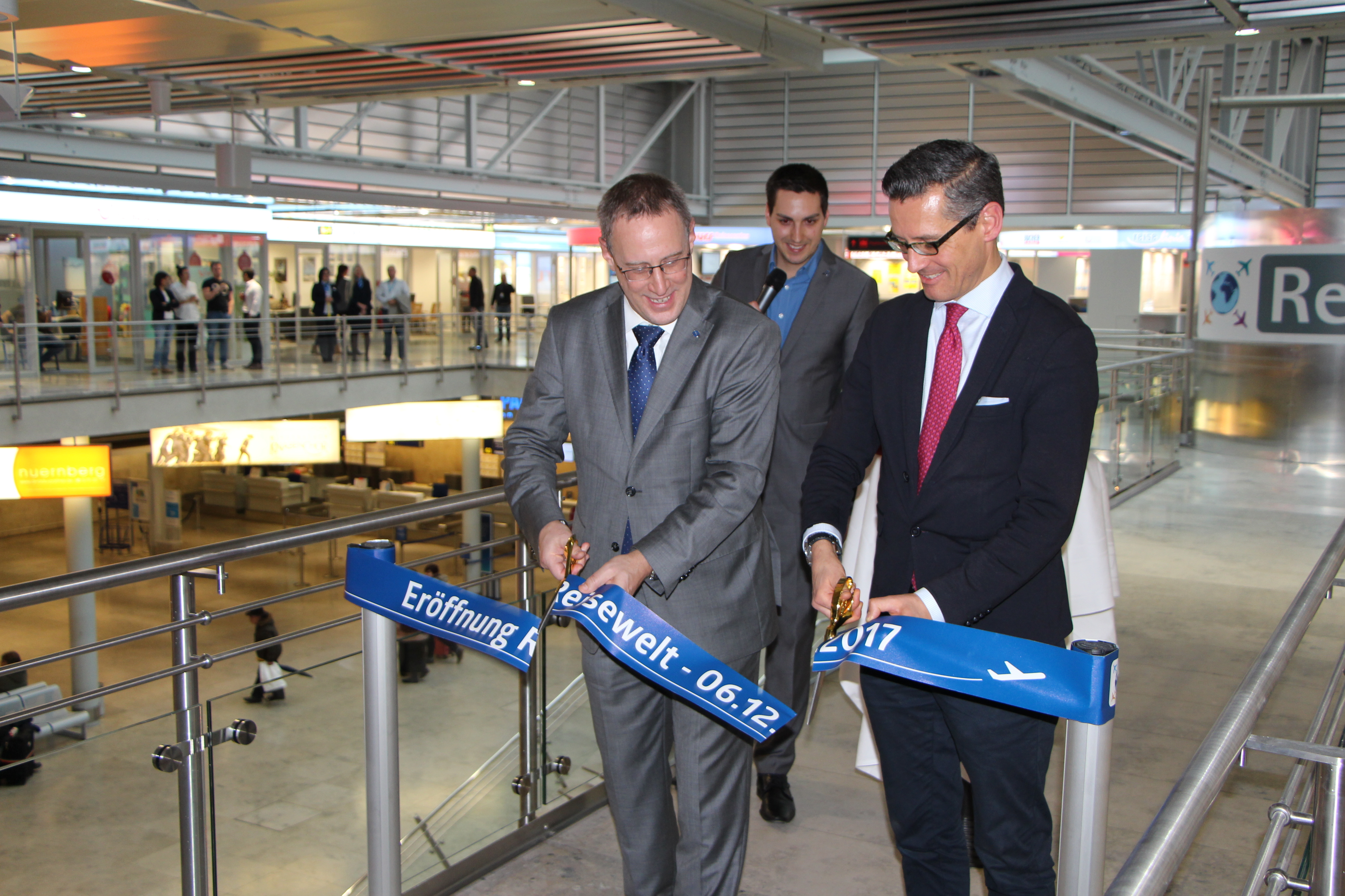 Dr. Michael Hupe (Flughafengeschäftsführer, l.) und Dr. Michael Fraas (Wirtschaftsreferent der Stadt Nürnberg) eröffnen mit dem Durchschneiden des Bandes die neue Reisewelt.
