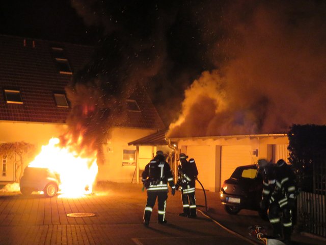 Löscharbeiten an einem brennenden Elektrofahrzeug und einer Garage