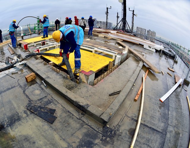 Arbeiter füllen die Schalung für den Aufzugsschacht vom Dach aus mit Beton. Foto: © Peter Maskow