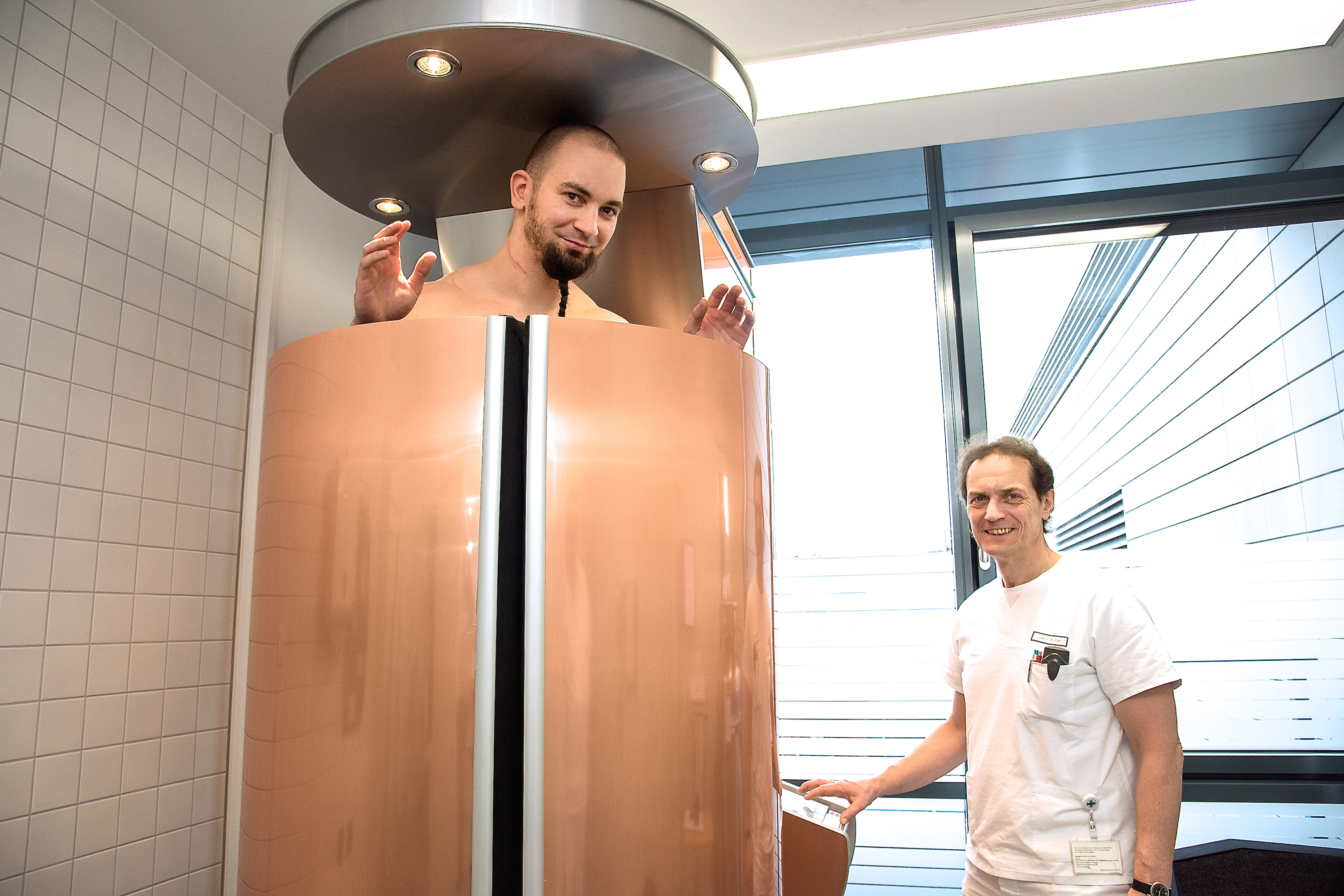 Trotz minus 130 Grad Celsius Umgebungstemperatur kann Leander Schubert (Masseur/Medizin 3) noch lächeln. Dr. Bleh (Oberarzt/Medizin 3) freut sich, seinen Patienten und weiteren Interessierten nun die Möglichkeit einer Kältetherapie bieten zu können. Foto: Uni-Klinikum Erlangen