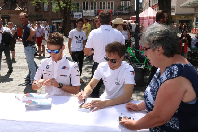 Lokalmatador marco Wittmann (l.) und Mercedes-AMG-Pilot Lucas Auer beim Autogramme schreiben. | Foto: John R. Braun