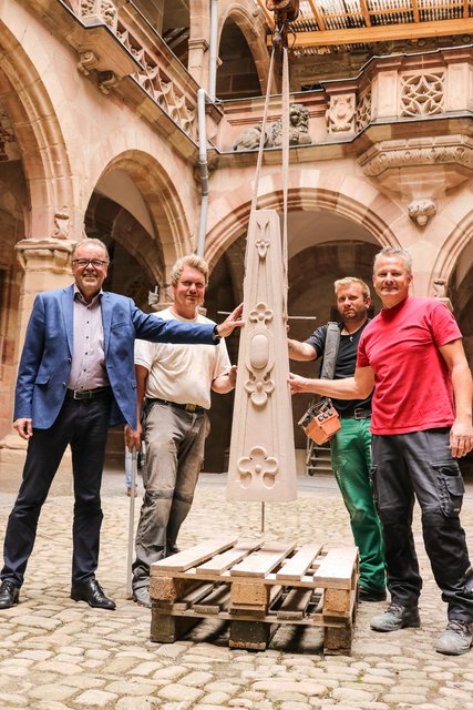 So sieht der Obelisk aus, der auf dem Bild bereits schwebend, gleich auf die Spitze des Nordgiebels gehoben wird. Altstadtfreunde Nürnberg Vorsitzender Karl-Heinz Enderle mit Steinmetz Harald Pollmann (Initiator des gesamten Vorhabens), Kranführer Patrick Forster und Steinmetzmeister Peter Franke (v.l.). | Foto: Nicole Fuchsbauer