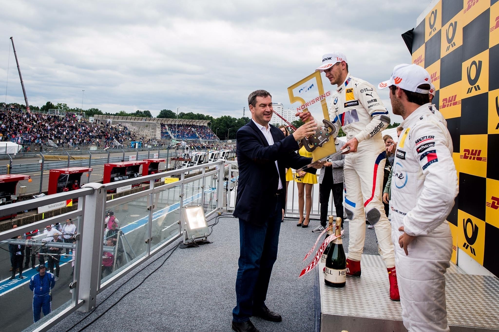Ministerpräsident Dr. Markus
Söder ehrt BMW-Fahrer Marco Wittmann für dessen Sieg im Sonntagsrennen. Es ist der erste Triumpf des Fürthers in seiner fränkischen Heimat.
