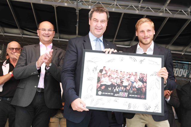 Kapitän Hanno Behrens überreicht Ministerpräsident Dr. Markus Söder ein Foto der erfolgreichen Aufstiegs-Mannschaft des 1. FC Nürnberg. | Foto: Udo Dreier