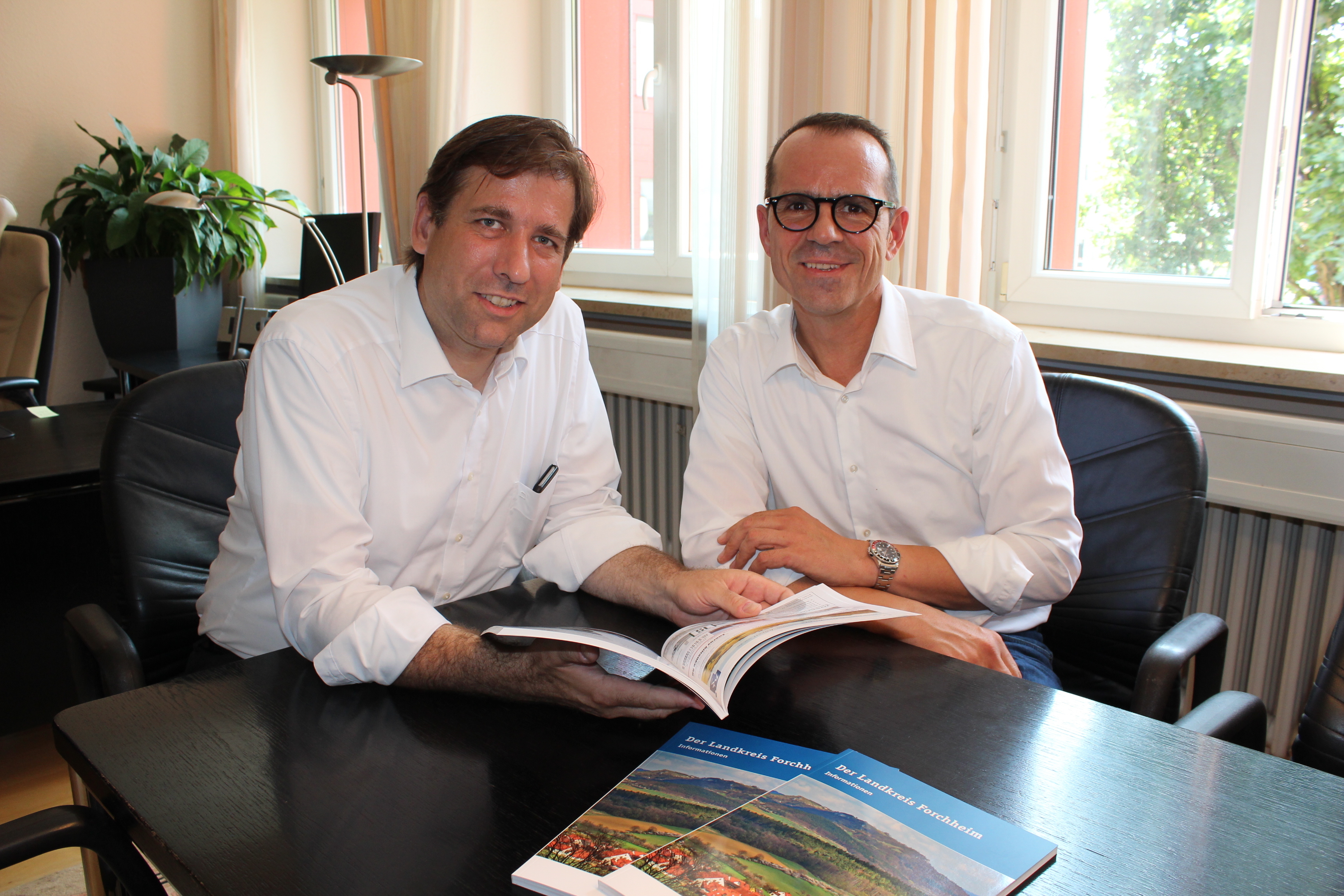 Geschäftsführer Raimond Heinzl übergibt die neue Broschüre an Landrat Hermann Ulm .