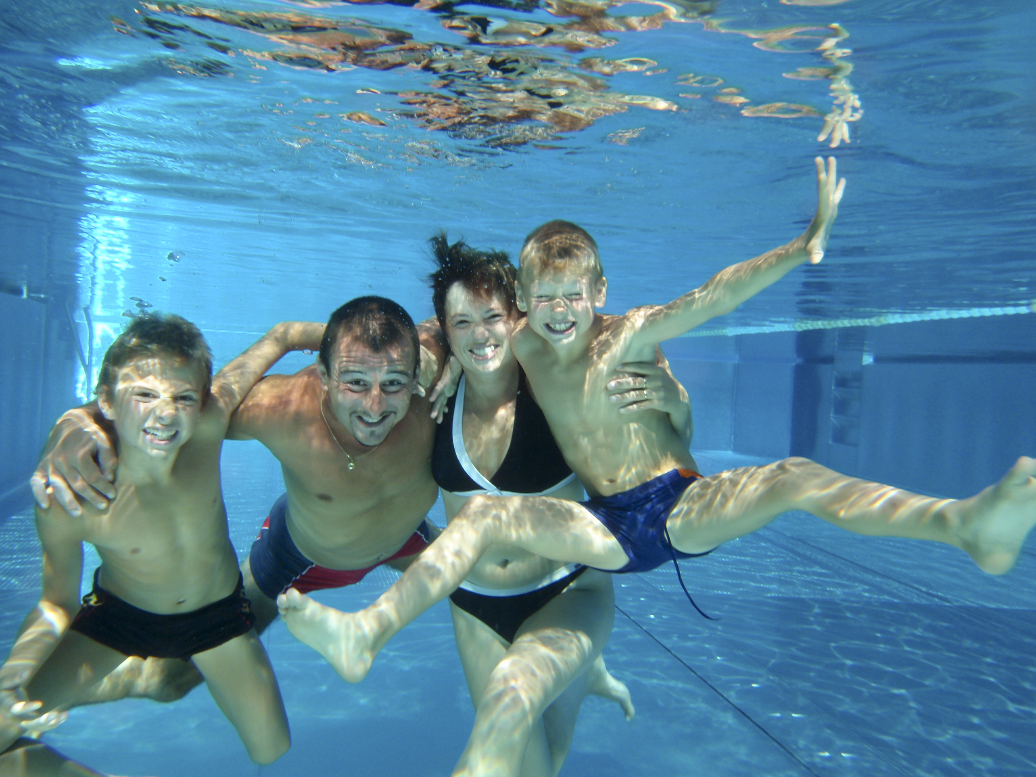 Vater, Mutter und zwei Söhne haben Spaß beim Familienfoto unter Wasser.