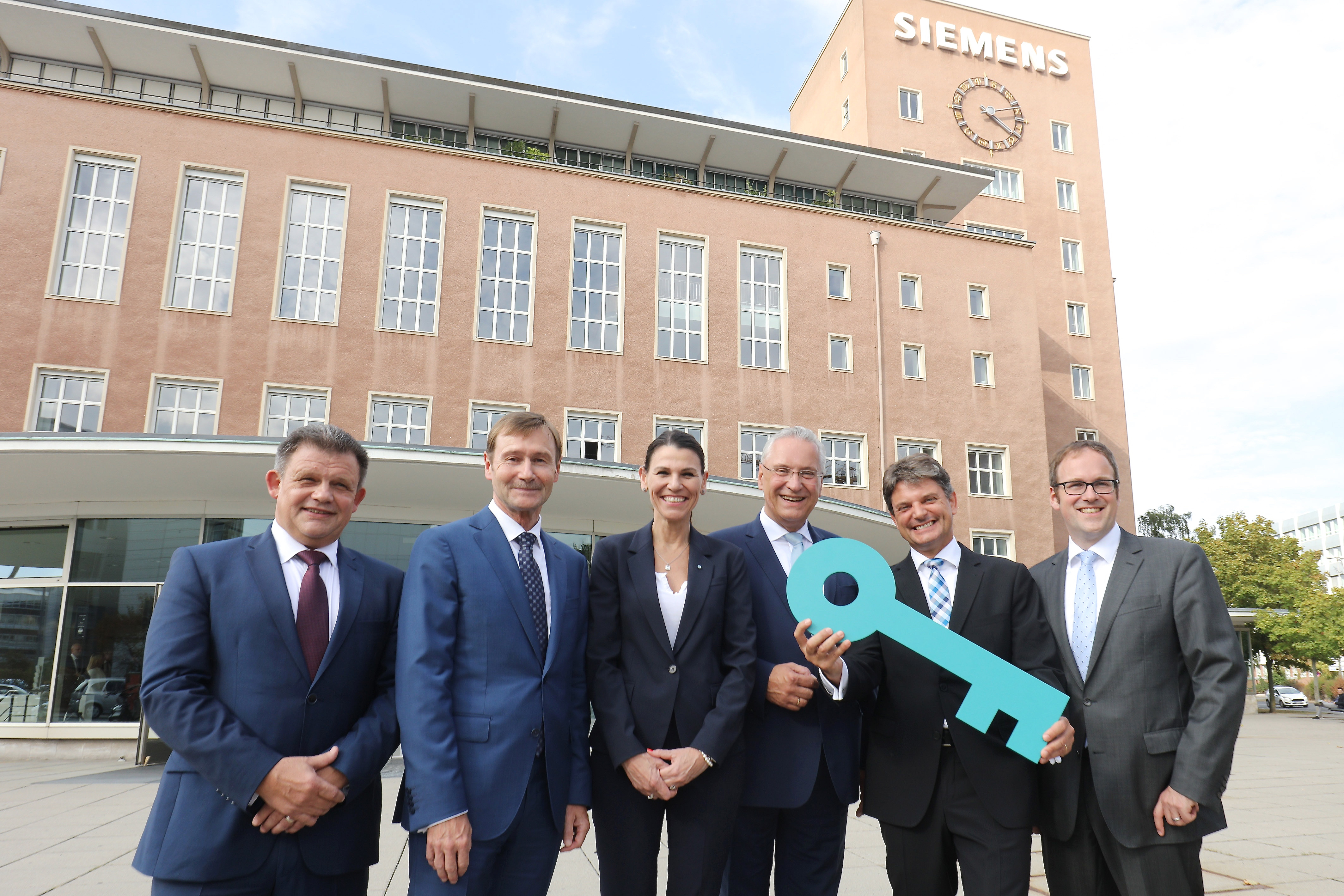 Symbolische Schlüsselübergabe: Dr. Zsolt Sluitner (CEO Siemens Real Estate), Klaus Helmrich (Siemens-Vorstand), Prof. Dr. med. Marion Kiechle (Staatsministerin für Wissenschaft und Kunst), Joachim Herrmann (Bayerischer Staatsminister des Innern und für Integration), Prof. Dr. Joachim Hornegger (Präsident der Friedrich-Alexander-Universität) und Dr. Florian Janik (Oberbürgermeister Erlangen / v.l.n.r.). Foto: © Kurt Fuchs
