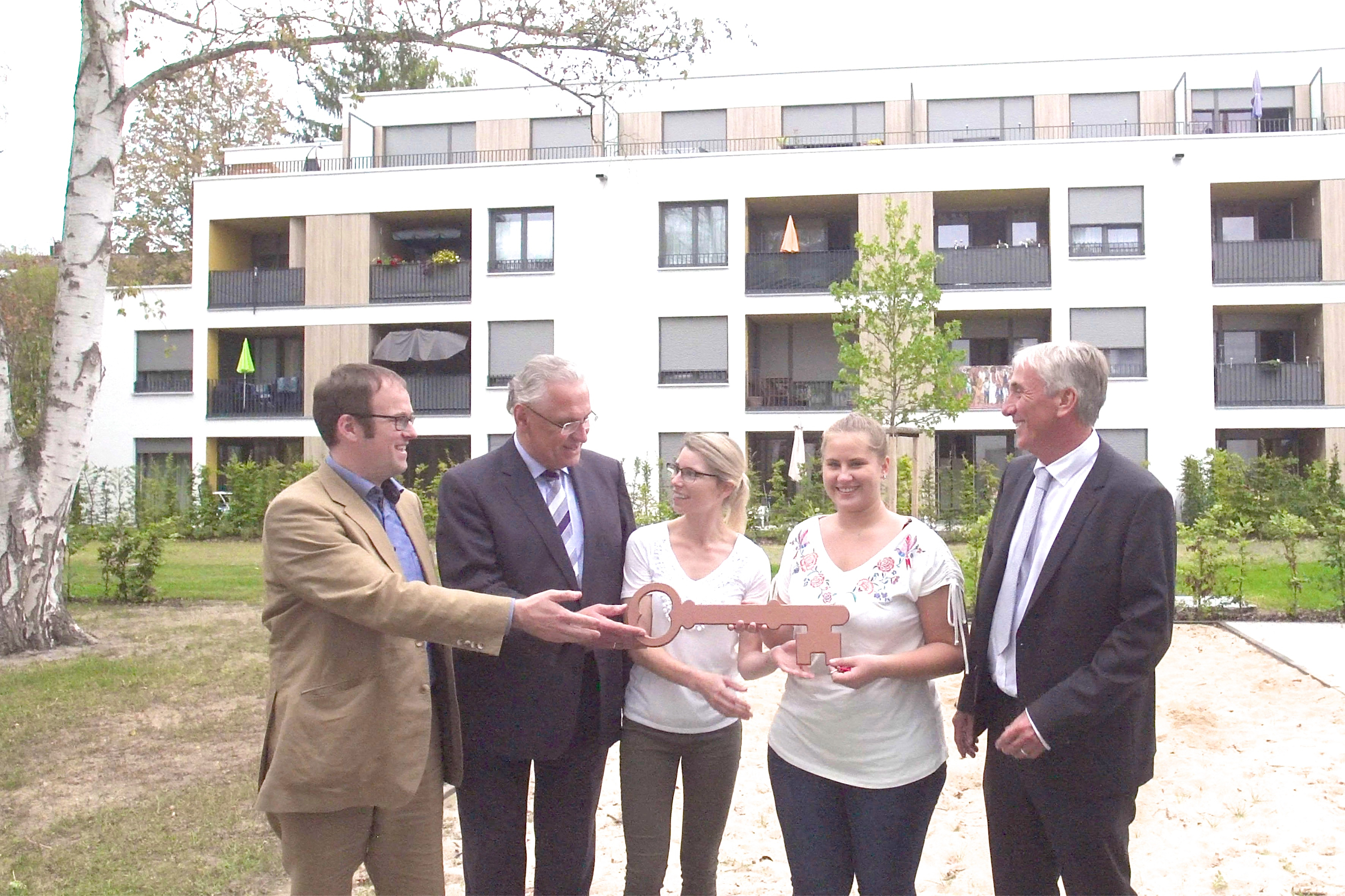 Erlangens Oberbürgermeister Dr. Florian Janik (l.), Staatsminister Joachim Herrmann (2.v.l.) und Gernot Küchler übergeben einen symbolischen Schlüssel an die Mieterinnen Deborah Thoma und Daniela Neufeld. Foto: © Kurt Fuchs