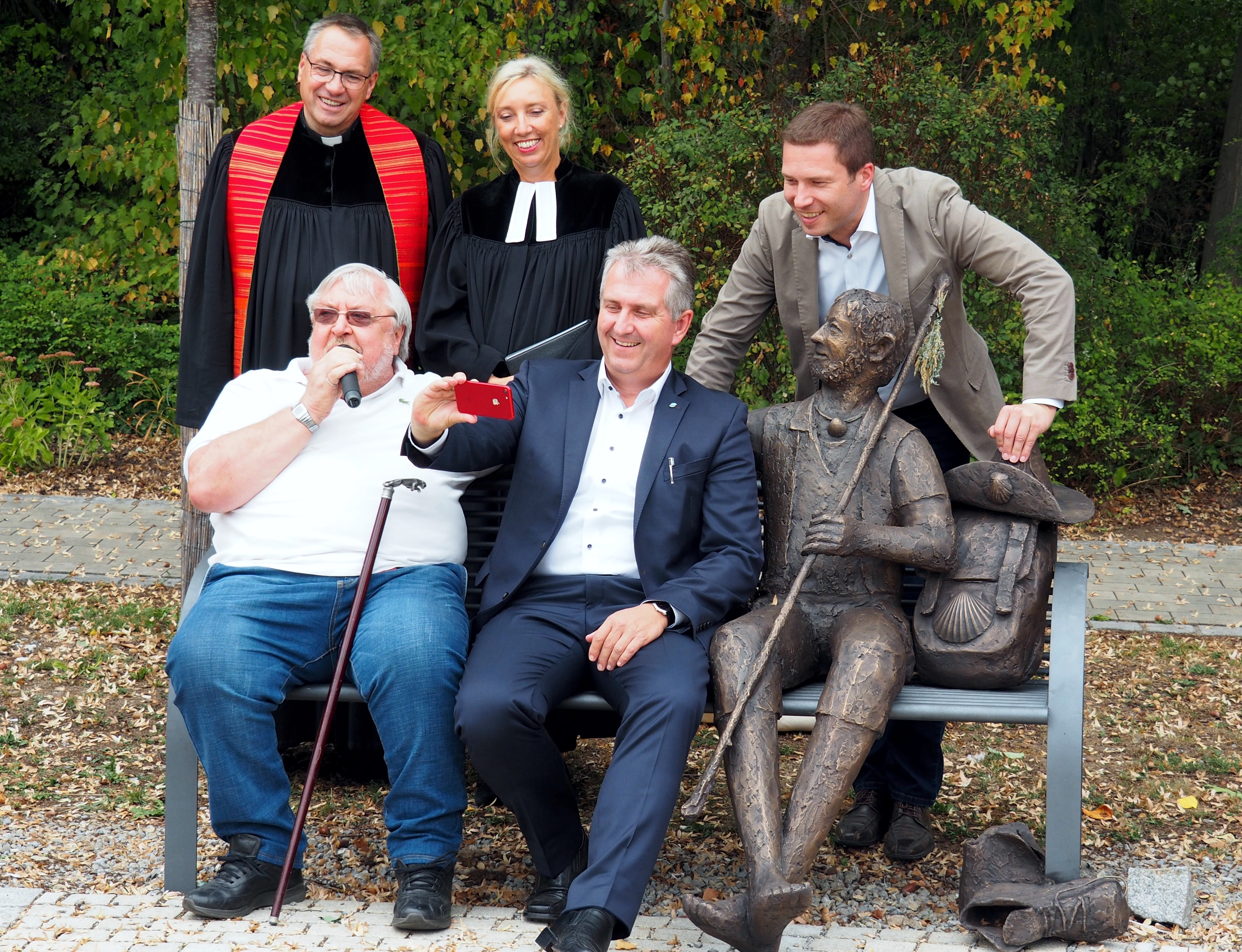 Der Künstler Theo Steinbrenner (auf der Bank links) und Kurt Krömer, Erster Bürgermeister der Stadt Stein, dahinter stehend, Pfarrer Reiner Redlingshöfer, Pfarrerin Birgit Winkler und Landrat Matthias Dießl.